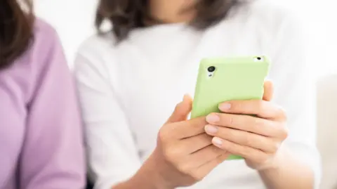Two hands are seen holding a mint green smartphone.
