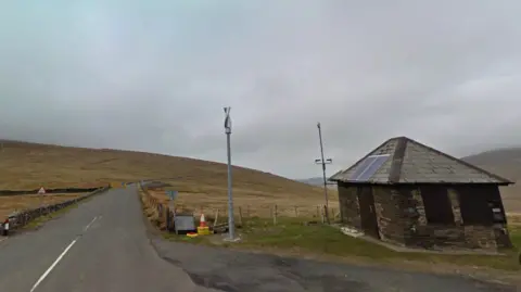 Google The Ben-y-Phott Road, which turns off from the Mountain Road. It is a narrow windy road across a hill and there is a small hut on the right at the turn off.