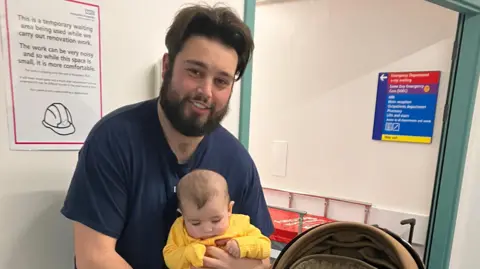 Brett holding one of his children in the Emergency Department in Basingstoke