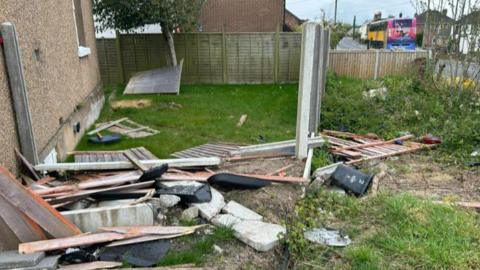 A garden full of debris, including a smashed fence