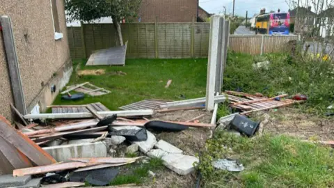 A garden full of debris, including a smashed fence