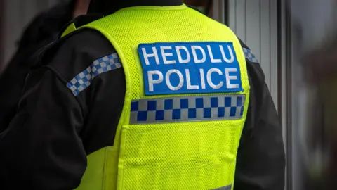 Getty Images A close-up of a police officer's uniform with the words Heddlu and Police written on the back.