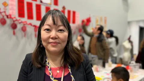 A woman from Hong Kong stands in front of Lunar New Year posters. 