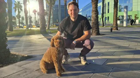 Josh Feldberg Josh Feldberg crouches down next to his dog