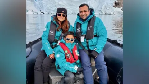 Keeyu (left) sitting next to her husband Amit (right) with Yuan (front and middle). All three are wearing turquoise waterproof jackets and life jackets around their necks.