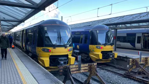 The platform at Bradford Forster Square with two blue and yellow trains. 