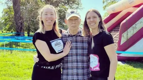 Steph and Lena Eastment stand in a field with their father Tony