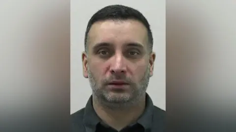 Northumbria Police Mugshot of Chahal. He has faint grey stubble and short black hair.