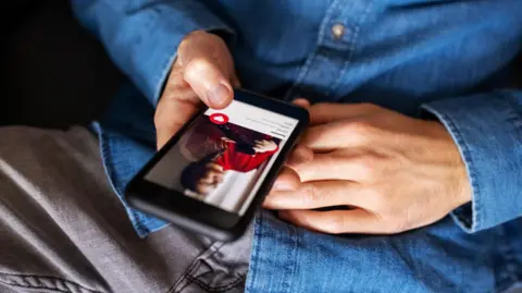 Close-up of a man using an online dating app on his mobile phone.