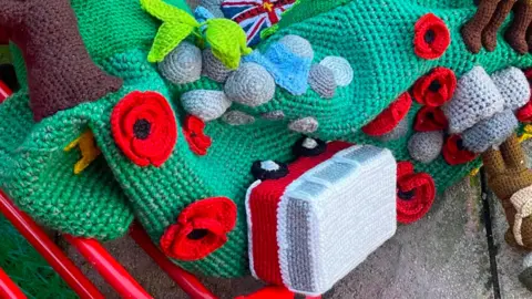 Chadburn family The topper on stone flags in a back garden it has knitted soldiers, poppies and a red and white camper van with the words Memory of Martin Chadburn in yellow along the side