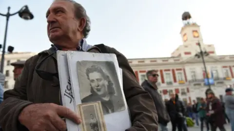 Getty Images A man holds a picture of a woman who went missing under Franco