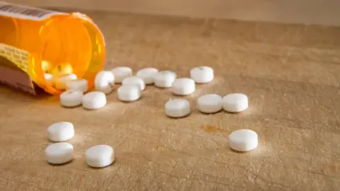 Getty Images Pills falling out of a bottle