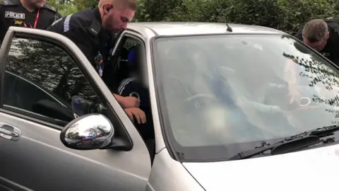 Police officers lean into car