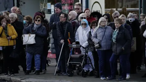 PA Media Members of the public line the street near to Iveagh Hall, in Leigh-on-Sea, the constituency office of murdered MP Sir David Amess, as they wait to pay their respects