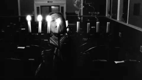 Nudrat Afza Woman blowing out candles on menorah