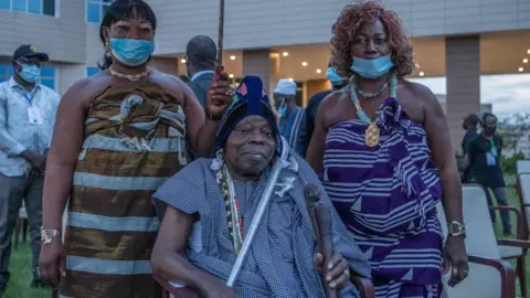 AFP Dah Sagbadjou Glele (C), is seen during a ceremony where artefacts, some considered sacred in Benin, arrived at the presidential palace in Cotonou on November 10, 2021