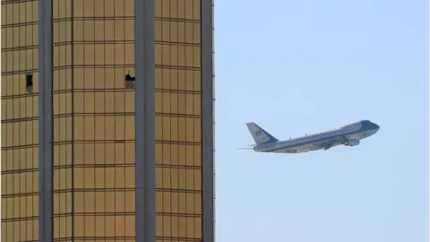 Reuters Air Force One passes to the right of the gold-coloured windows of the Mandalay hotel, two of which are shattered from the gunfire during the attack
