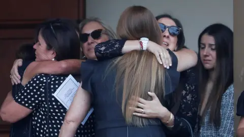 Mourners hug each other