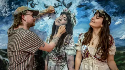 Plaster Communciations Artist and model in front of painting of flower girl