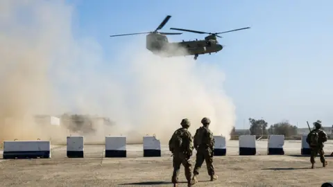 Getty Images US troops walk as a US Army C-47 Chinook helicopter flies over the village of Oreij, south of Mosul, on February 22, 2017