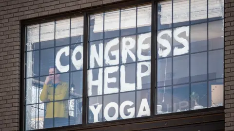 Corey Hilz Dave Giacomin stands by the window of his studio with the words "Congress help yoga" painted on the window