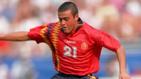 Getty Images Luis Enrique concentrates on his run, arms in the airs, at the 1994 World Cup. He's wearing a red shirt, number 21, with diamonds on the right-hand side.