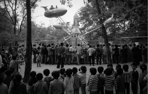 ADRIAN BRADSHAW A crowd watches a ride at a fairground