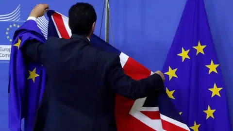 Reuters EU official hanging a Union Jack flag next to an EU flag