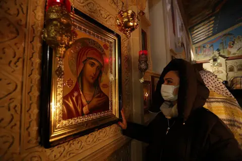 Aziz Karimov / Getty Images A woman prays during an Orthodox Christmas service