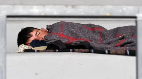 AFP A young migrants sleeps on the stands of a stadium in Mexico City