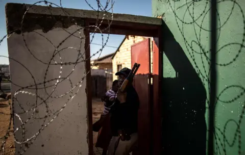 AFP A South African police officer stands in the door way of a looted foreign-owned shop in Soweto,