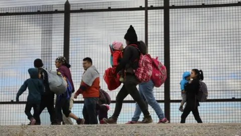 Getty Images Central American immigrants walk along the border fence after crossing the Rio Grande from Mexico on February 01, 2019 in El Paso, Texas