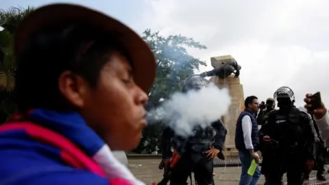 EPA An indigenous person performs a ritual in front of the authorities after protesters knocked down the statue of the founder of the city, Spanish conqueror Sebastian de Belalcazar, during the protests against the tax reform called by the workers" centrals in Cali, Colombia, 28 April 2021.