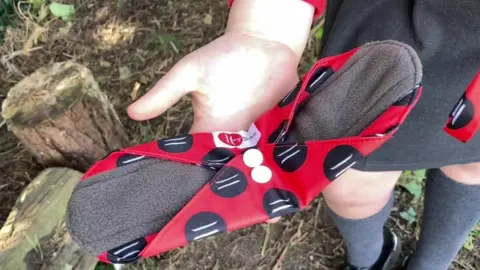 BBC reusable pad held in schoolgirls' palm