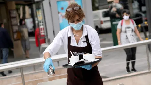 Reuters A waitress wearing a protective mask and gloves