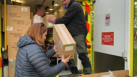 People loading boxes into an ambulance