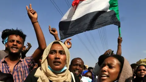 AFP Sudanese protesters flash victory signs and lift national flags as they demonstrate on 60th Street in the capital Khartoum, to denounce overnight detentions by the army of government members, on October 25, 2021.