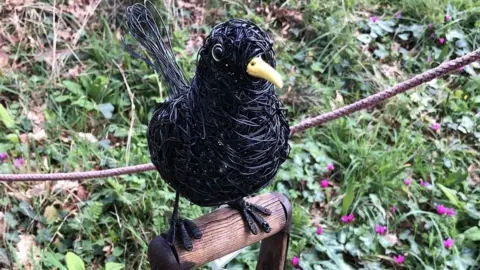 Joanne Fryer A sculpture of a black bird sitting on a fork handle at Bristol University Botanic Gardens