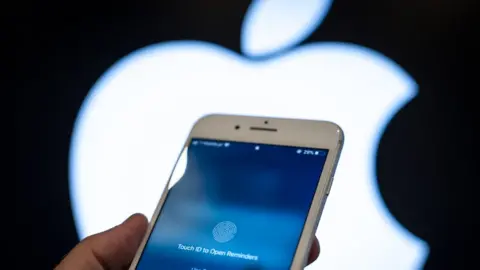 Getty Images An iPhone locked awaiting a thumbprint is seen in front of a glowing Apple logo in the background