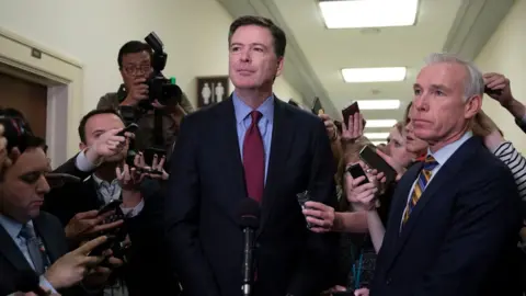 AFP Former FBI Director James Comey (C) talks to reporters following a closed House Judiciary Committee meeting in December 2018