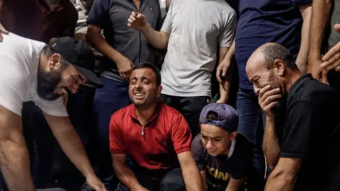  EYAD BABA/AFP Family members and relatives mourn over the bodies of Palestinian militants killed in the latest infiltration operation into Israel, at the mortuary of a hospital in Gaza City on October 7, 2023.