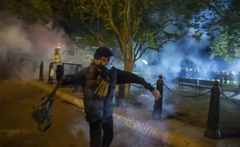 Getty Images A protesters throws a stone at police (in the background) in Washington DC. Photo: 31 May 2020