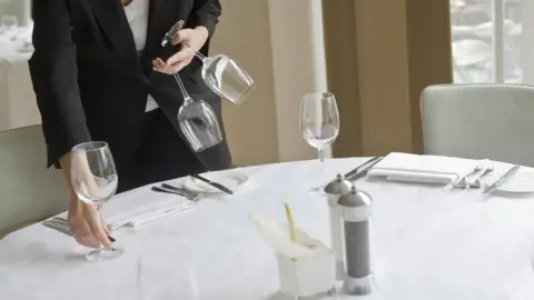 Getty Images Woman setting table in restaurant