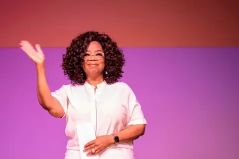 AFP US TV personality Oprah Winfrey waves during an event to mark 100 years since the birth of Nelson Mandela, at the University of Johannesburg, Soweto Campus, in Johannesburg, South Africa - 29 November 2018