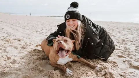 Jess Eley Jess Eley and Dora the dog on the sandy beach at Southbourne