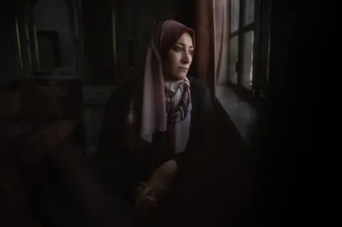 BBC Areej Jabari, a resident of H2, looks out of her window onto the street, which she can no longer use freely.