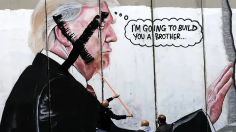 EPA Palestinians paint an X over the face of a picture of Donald Trump on the Israeli separation wall in Bethlehem, West Bank, on 7 December 2017