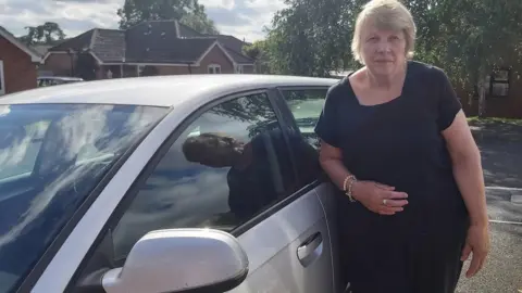 June Leatheam June Leatham, 72, in front of her car