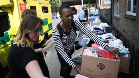 Getty Images Women carrying donated clothes on 16 June