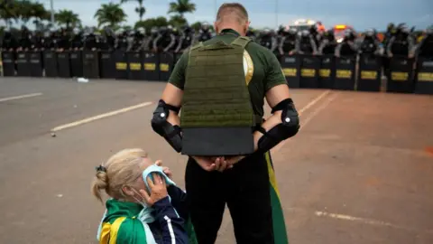 Reuters One Bolsonaro supporter shields another in Brasilia on Sunday